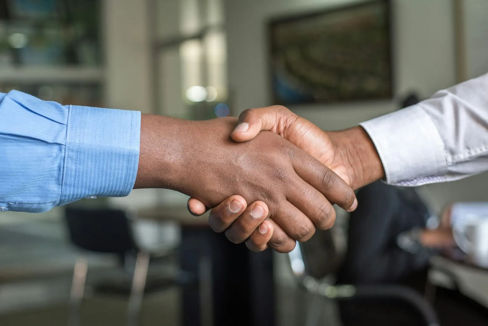 Two people shaking hands across a table after agreeing on a placement